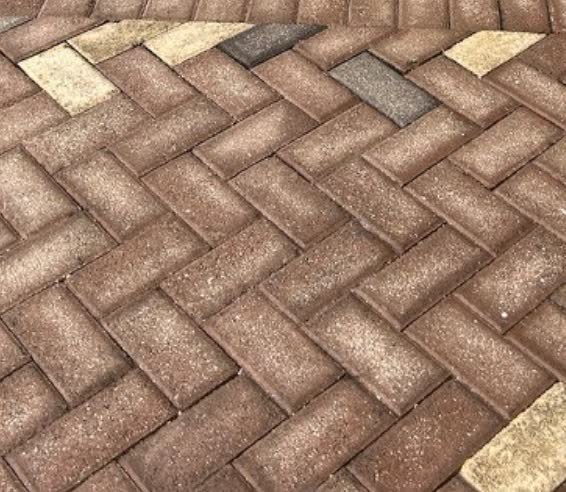 Herringbone paver path after pressure washing, restored to warm terracotta.